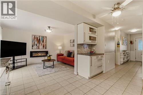 Open-concept living area with tile flooring and a modern electric fireplace - 17 Piper Place, Caledonia, ON 