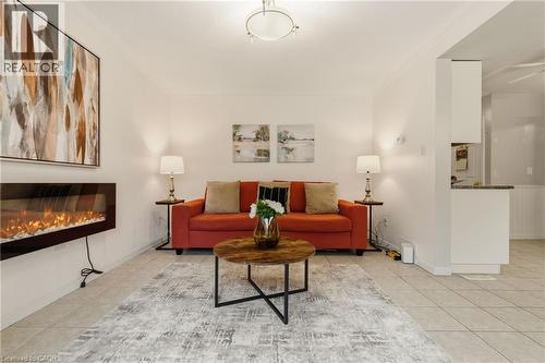 Living area featuring a wall-mounted electric fireplace, tile flooring, crown molding, and recessed lighting - 17 Piper Place, Caledonia, ON 
