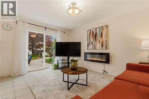 Tiled flooring throughout a bright living area, featuring a wall-mounted electric fireplace and crown molding - 17 Piper Place, Caledonia, ON 