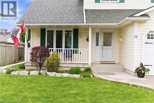 Exterior featuring light-colored siding, a covered front porch, and a dedicated garage entrance - 17 Piper Place, Caledonia, ON 