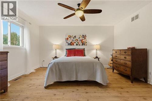 Bedroom featuring wood-finish flooring, a ceiling fan with integrated lighting, and a window with white trim - 17 Piper Place, Caledonia, ON 