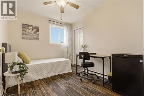 Wood-finish flooring throughout, featuring a ceiling fan with integrated lighting, a paneled door, and a window with white trim - 17 Piper Place, Caledonia, ON 