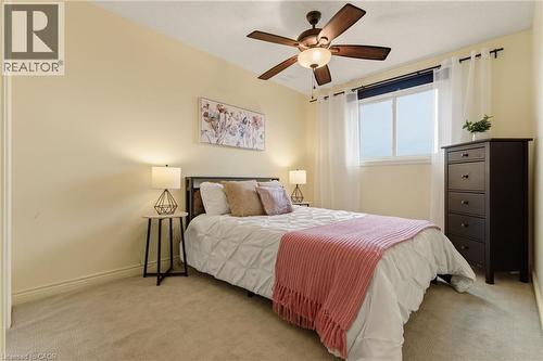 Carpeted room featuring a ceiling fan with integrated lighting, a window with white sheers, and light-toned walls - 17 Piper Place, Caledonia, ON 