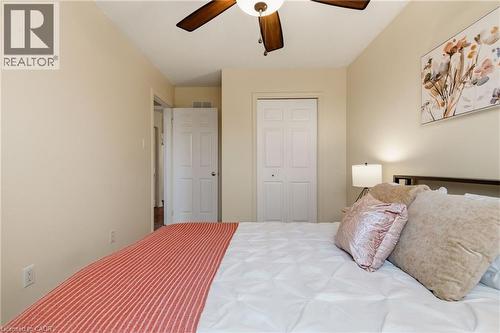 Bedroom featuring light neutral wall tones, a ceiling fan with wood-finish blades, and white bi-fold closet doors - 17 Piper Place, Caledonia, ON 