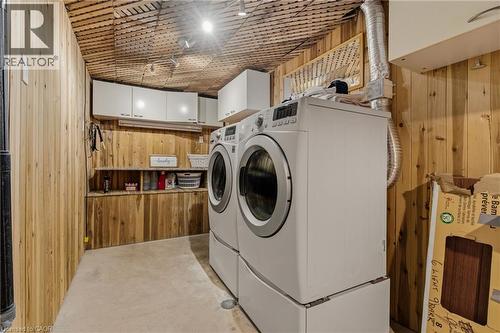 Dedicated laundry area featuring wood-finish wall paneling, a wood-finish ceiling, track lighting, built-in shelving, and white cabinetry - 17 Piper Place, Caledonia, ON 