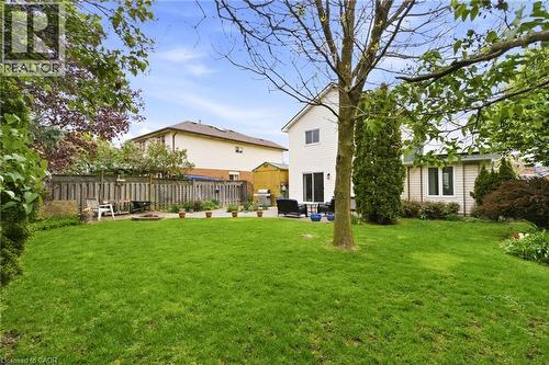 Spacious backyard featuring a lush lawn, mature trees, and a stone patio area - 17 Piper Place, Caledonia, ON 