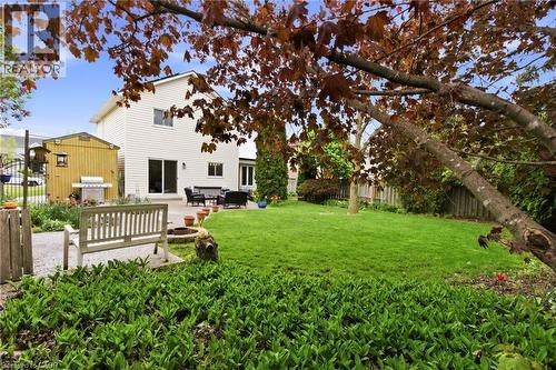 Manicured rear lawn with a spacious patio, a built-in fire pit, and a separate storage shed - 17 Piper Place, Caledonia, ON 