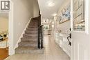 Entryway featuring ceramic tile flooring, a carpeted staircase with dark wood banister, and built-in shelving - 17 Piper Place, Caledonia, ON 