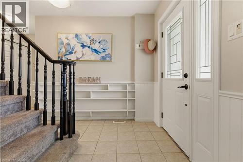 Foyer featuring tile flooring, white wainscoting, an entry door with decorative glass, and a built-in shelving unit - 17 Piper Place, Caledonia, ON 