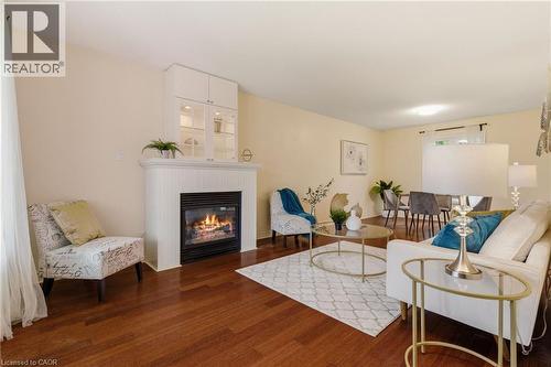 Living area featuring wood-finish flooring, a white mantel, and an integrated fireplace with a display cabinet - 17 Piper Place, Caledonia, ON 