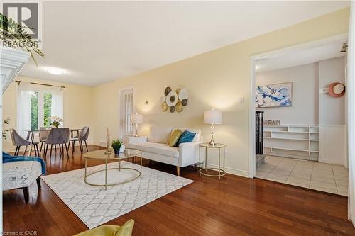 Open-concept living space featuring wood-finish flooring, a dining area with a window overlooking greenery, and an entryway with built-in shelving - 17 Piper Place, Caledonia, ON 