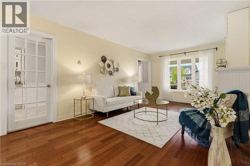 Spacious living area featuring wood-finish flooring, a large bay window, and a white French door with multiple glass panes - 17 Piper Place, Caledonia, ON 