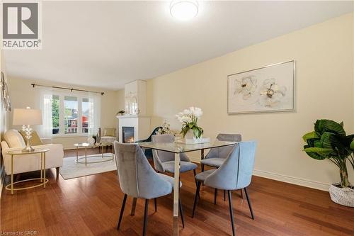 Open-concept living space featuring wood-finish flooring, a contemporary fireplace with mantel, and a multi-pane window - 17 Piper Place, Caledonia, ON 