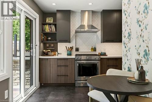 Contemporary kitchen featuring a stainless steel range with matching hood, white subway tile backsplash, and dark wood-finish cabinetry - 99 Hillcrest Avenue, Hamilton, ON 