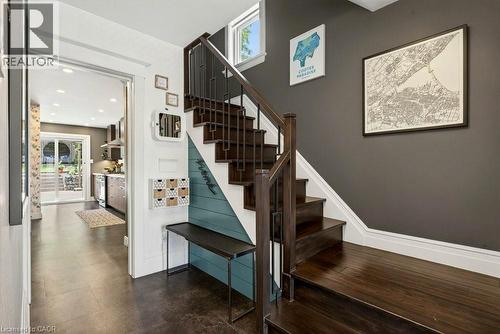 Wood-finish flooring extending from the entryway to the kitchen, dark wood staircase with contemporary metal railings, and a built-in bench - 99 Hillcrest Avenue, Hamilton, ON 
