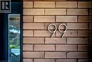 Brick exterior wall with modern metallic house numbers and an adjacent glass-paneled entry - 99 Hillcrest Avenue, Hamilton, ON 