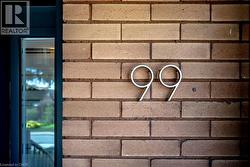 Brick exterior wall with modern metallic house numbers and an adjacent glass-paneled entry - 