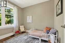 Neutral-toned room featuring a large multi-pane window with white trim, wood-finish flooring, and white baseboards - 