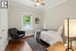 Bedroom featuring wood-finish flooring, a contemporary ceiling fan, and crown molding - 