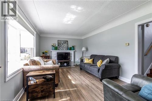 Living area featuring wood-finish flooring and a stone-clad fireplace - 20 West 1St Street, Hamilton, ON 