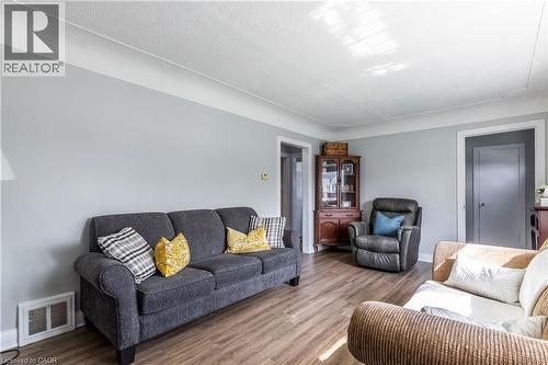 Living area featuring wood-finish flooring, light gray wall paint, white trim, and a textured white ceiling - 20 West 1St Street, Hamilton, ON 