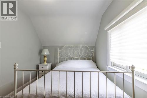 Attic room with sloped ceiling, light gray walls, and a window with white blinds - 20 West 1St Street, Hamilton, ON 