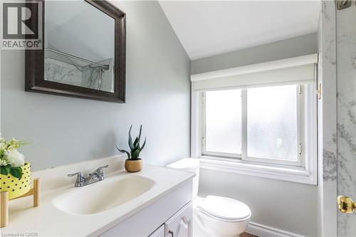 Bathroom featuring a white vanity with an integrated sink, chrome faucet, and framed mirror - 20 West 1St Street, Hamilton, ON 