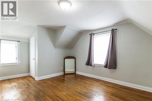 Spacious room featuring hardwood flooring, light gray walls, white trim, and two windows - 20 West 1St Street, Hamilton, ON 