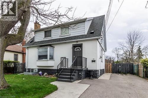 Two-story residence featuring a gray asphalt shingle roof and light-colored siding - 20 West 1St Street, Hamilton, ON 