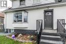 Exterior facade featuring a dark gray paneled entry door with an arched glass insert, flanked by black metal handrails - 20 West 1St Street, Hamilton, ON 