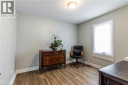 Room featuring wood-finish flooring, light gray walls, a single window with blinds, white baseboards, and a ceiling-mounted light fixture - 20 West 1St Street, Hamilton, ON 