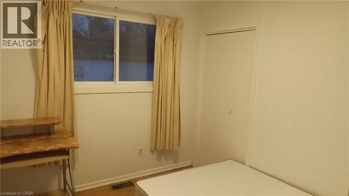 Window with white frame and neutral drapes, light wood-finish flooring, white wall paint, and a white closet door - 68 Austin Drive, Waterloo, ON - Indoor Photo Showing Other Room