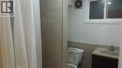 Modern bathroom featuring a single window, white tiled half-wall, wood-finish vanity with an integrated sink, and contemporary fixtures - 68 Austin Drive, Waterloo, ON - Indoor Photo Showing Bathroom