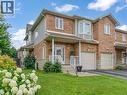 Brick and siding exterior featuring a covered front porch, integrated single-car garage, bay window, and a landscaped front yard with established plantings - 2229 Walkers Line Unit# 6, Burlington, ON  - Outdoor With Facade 