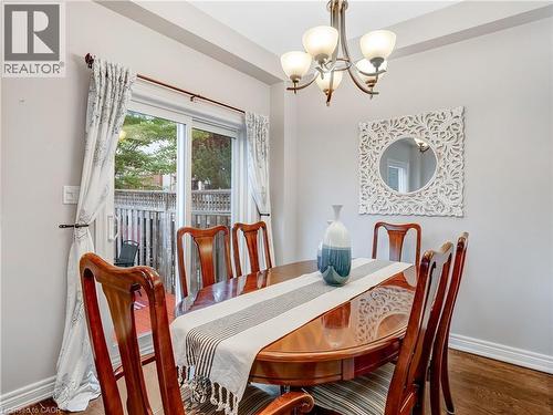 Dining area featuring wood-finish flooring, a contemporary chandelier, and a sliding glass door providing access to an outdoor area - 2229 Walkers Line Unit# 6, Burlington, ON - Indoor Photo Showing Dining Room