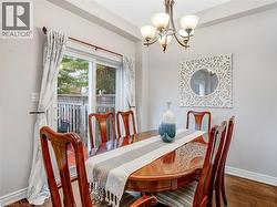Dining area featuring wood-finish flooring, a contemporary chandelier, and a sliding glass door providing access to an outdoor area - 