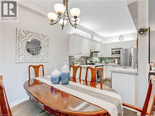 Open-concept kitchen and dining area featuring white cabinetry, stainless steel appliances, light-toned countertops, and a stone-tiled backsplash - 2229 Walkers Line Unit# 6, Burlington, ON - Indoor Photo Showing Dining Room