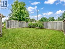 Expansive backyard featuring a manicured lawn, a full-height wooden privacy fence, mature perimeter trees, and established shrubbery - 