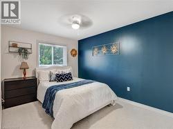 Bedroom featuring a prominent accent wall, light carpeting, and a window with outdoor views - 