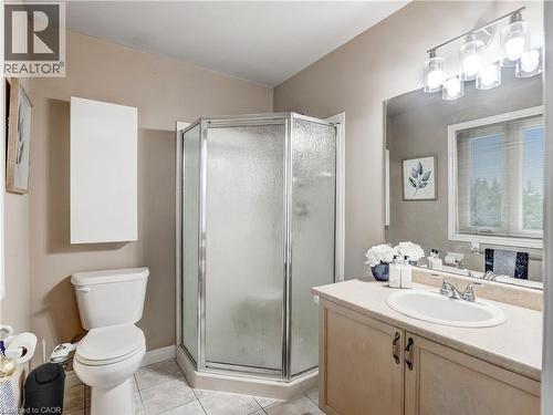 Shower enclosure with frosted glass and chrome trim, vanity with laminate countertop and integrated sink, light wood-finish cabinetry, tile flooring, and a large wall-mounted mirror - 2229 Walkers Line Unit# 6, Burlington, ON - Indoor Photo Showing Bathroom