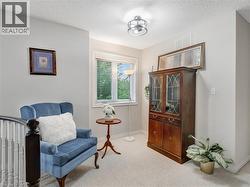 Carpeted landing featuring a window with blinds, a wood-finish display cabinet with glass doors, and a semi-flush mount ceiling light - 