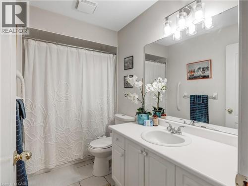 Bathroom featuring a single vanity with a white countertop and integrated sink, white cabinetry with round knobs, a large wall-mounted mirror, and a multi-bulb vanity light fixture - 2229 Walkers Line Unit# 6, Burlington, ON - Indoor Photo Showing Bathroom