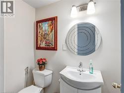 Bathroom featuring a white toilet, white vanity with integrated sink, and an overhead light fixture - 