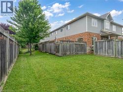 Fenced backyard with lawn and mature tree - 