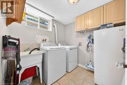 Dedicated laundry area featuring a utility sink, upper cabinetry, and a window - 