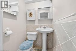 Bathroom featuring a pedestal sink, ceramic tile wainscoting, and a wall-mounted medicine cabinet - 