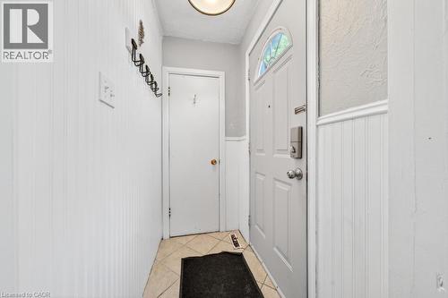 Entryway featuring a paneled door with an arched decorative window, beadboard wainscoting, ceramic tile flooring, and a flush-mount ceiling light fixture - 420 Upper Gage Avenue, Hamilton, ON 