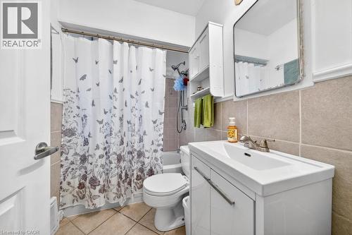 Bathroom featuring a single vanity with storage, a wall-mounted medicine cabinet, and a tiled shower/tub combination - 420 Upper Gage Avenue, Hamilton, ON 