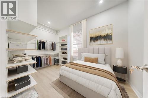 Light-filled bedroom featuring light wood-finish flooring and ample built-in closet organization. virtually staged - 1062 Cannon Street E, Hamilton, ON 