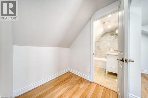 Spacious room featuring wood-finish flooring, recessed lighting, and a white-framed window. virtually staged - 1062 Cannon Street E, Hamilton, ON 